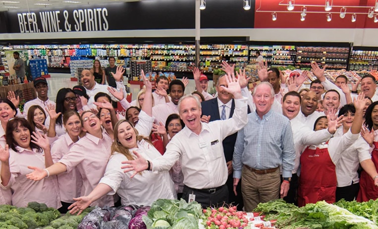 Group of associates inside a Winn-Dixie store smiling and cheering with their hands up